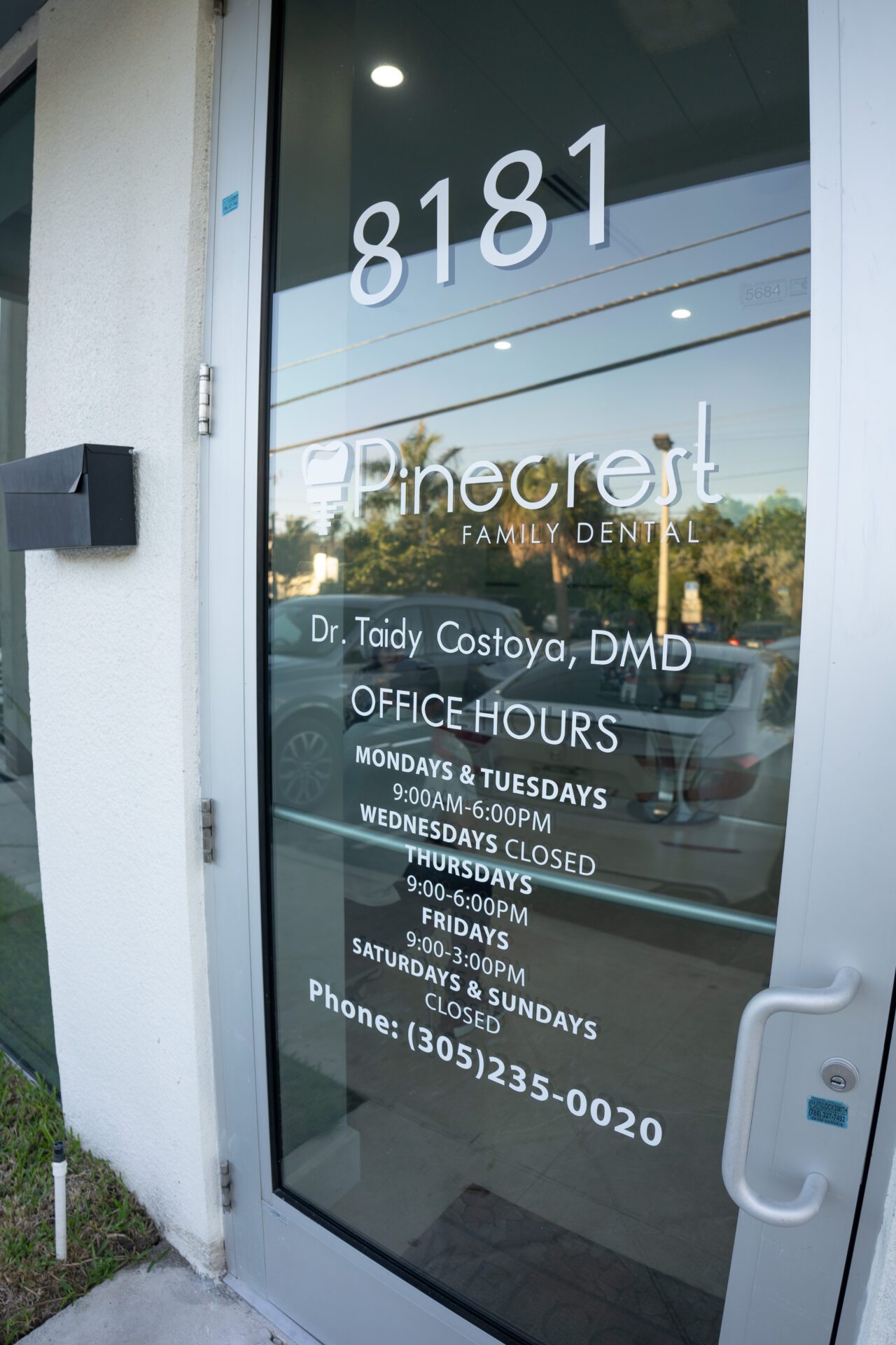 A glass entrance door for Pinecrest Family Dental featuring office hours, the name of Dr. Taidy Costoya, DMD, and the phone number (305) 235-0020.