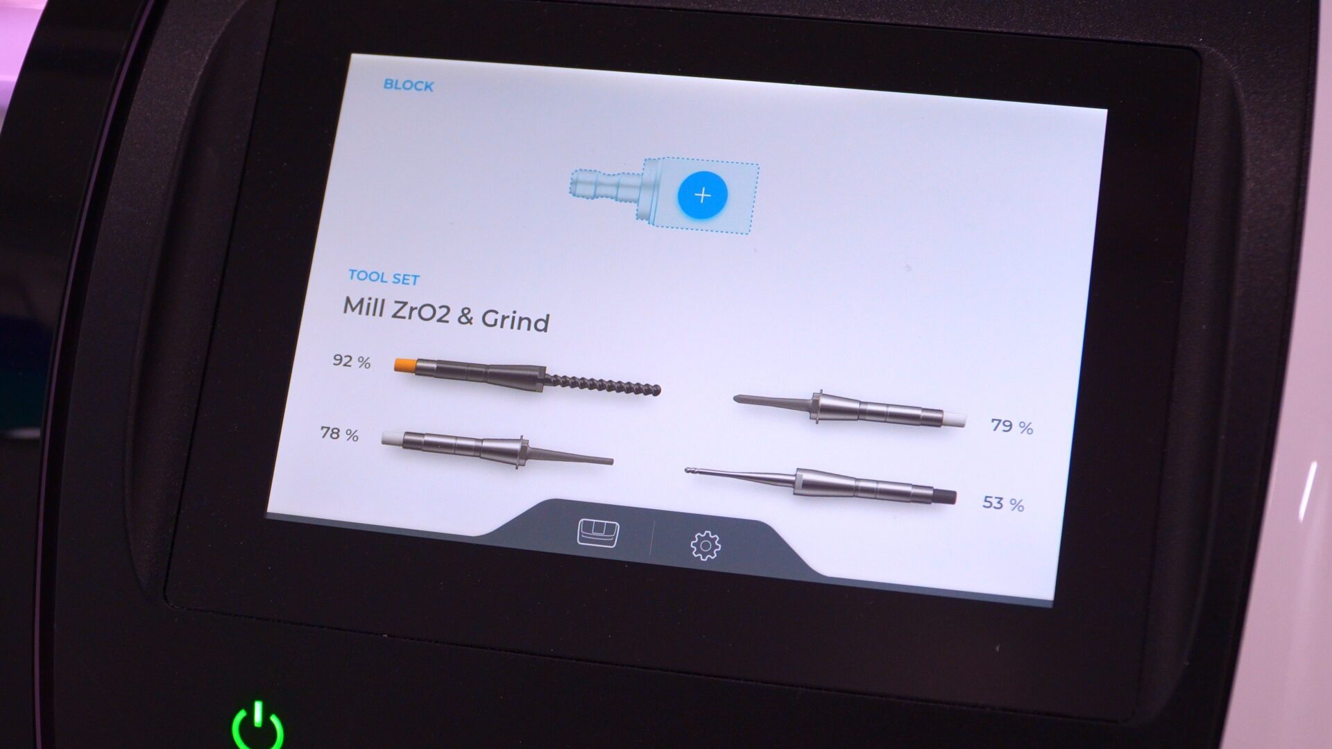 Close-up of a touchscreen interface on a dental milling machine displaying 'Mill ZrO2 & Grind' tool sets with percentage indicators for tool life.