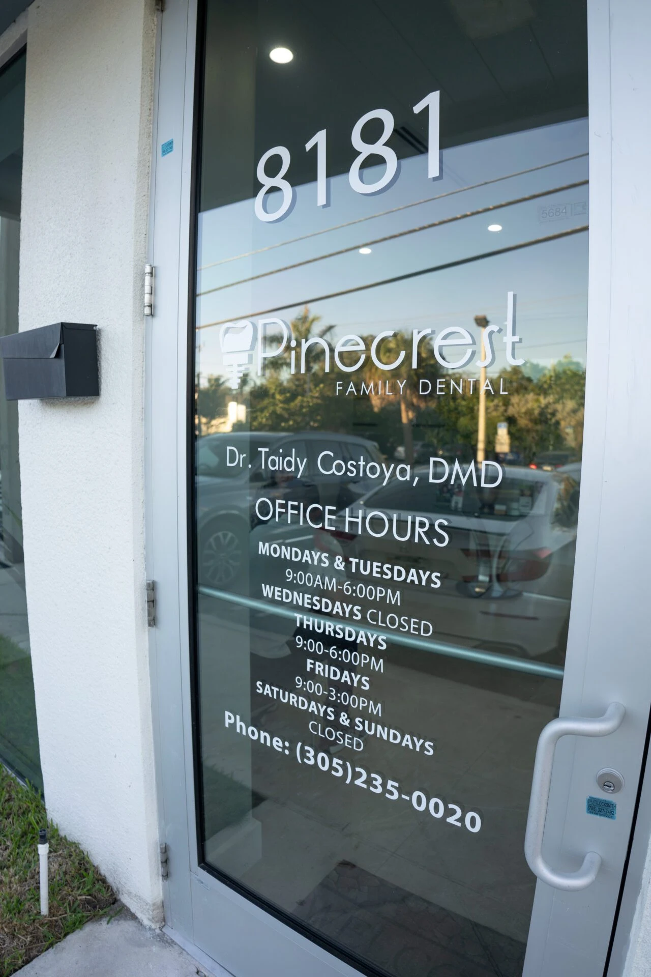 A glass entrance door for Pinecrest Family Dental featuring office hours, the name of Dr. Taidy Costoya, DMD, and the phone number (305) 235-0020.